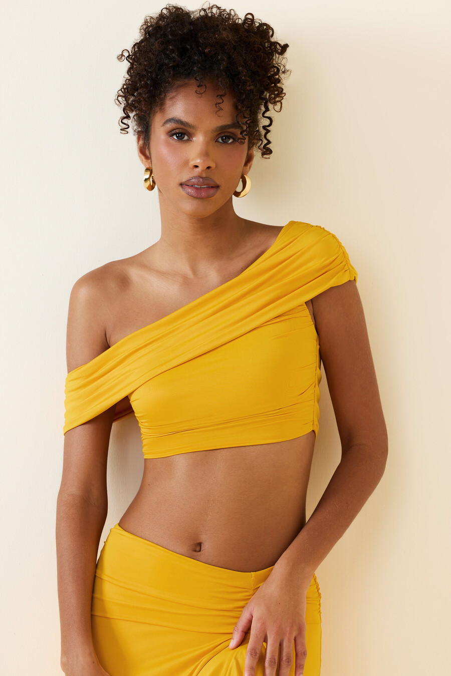 asymetrický nařasený crop top s odhalenými rameny ve zlatavě žluté barvě